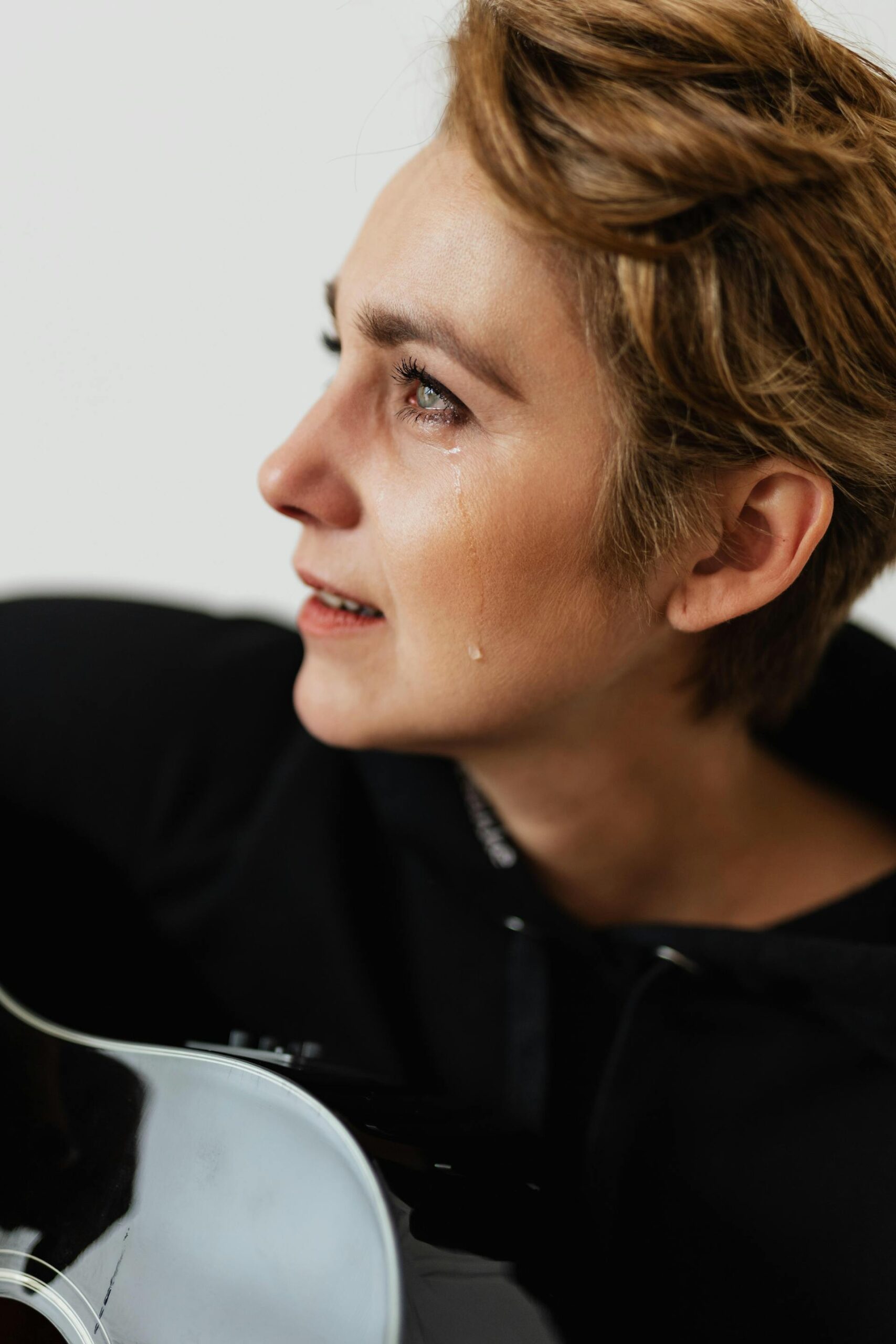 depressed woman, smiling and crying, while playing guitar