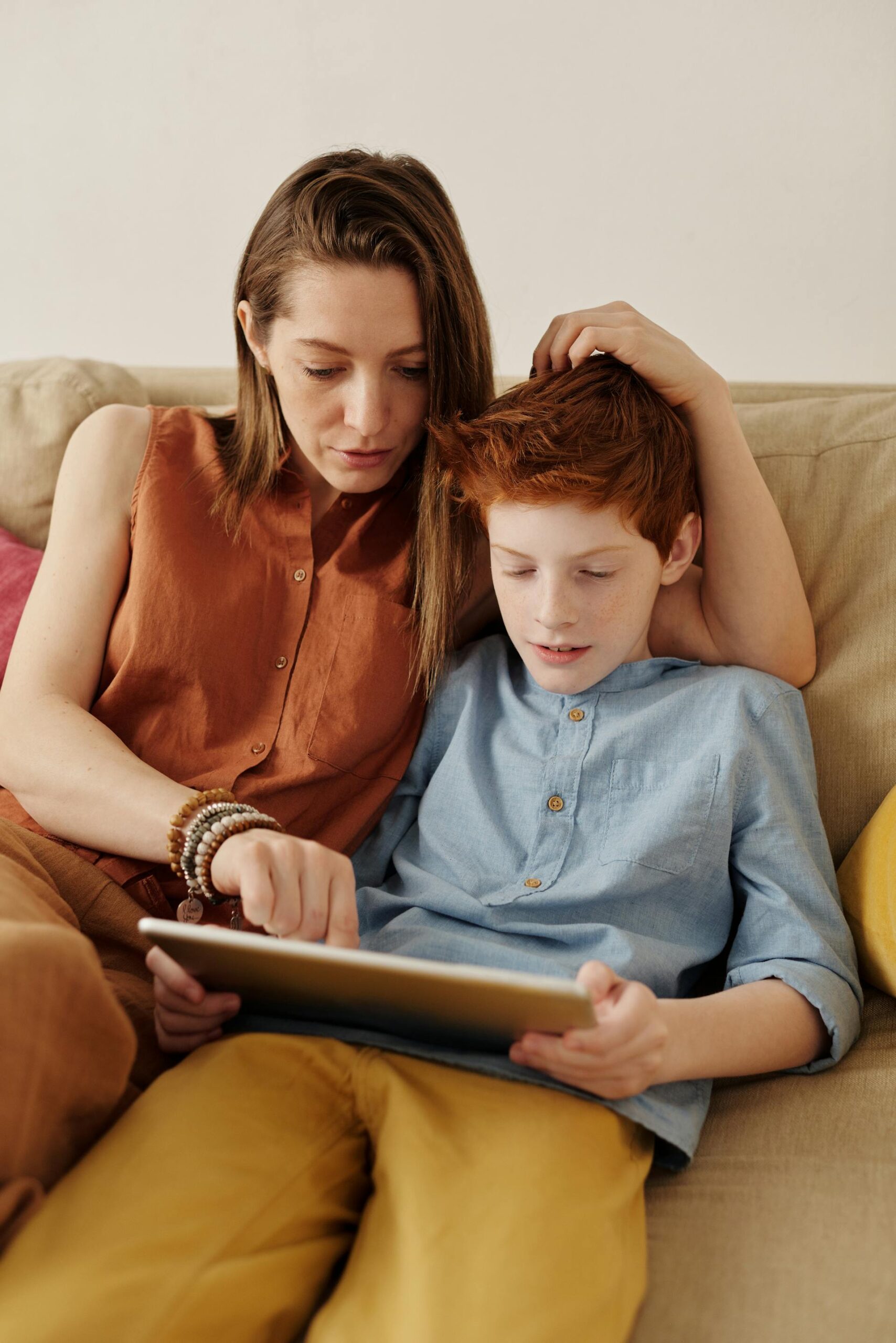 mom sitting with her son, looking at an ipad, worried