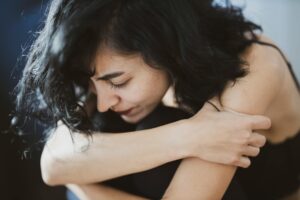 woman with high functioning anxiety hugging herself, looking overwhelmed